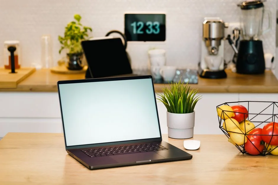 Close-up of hands typing on a laptop next to a cup of coffee on a wooden desk.